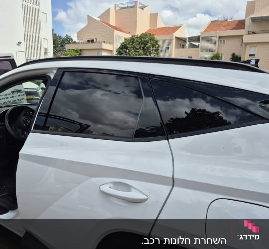 רכב עם חלונות כהים וחלקי בניין ברקע